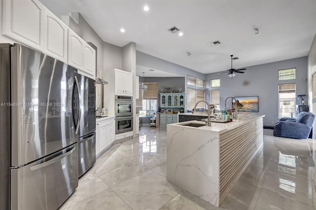 kitchen with ceiling fan, sink, white cabinets, appliances with stainless steel finishes, and light stone countertops