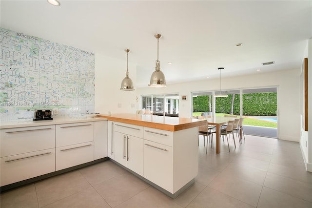 kitchen featuring pendant lighting, white cabinets, and light tile patterned flooring