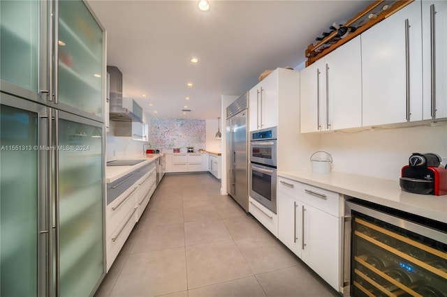 kitchen featuring wall chimney exhaust hood, white cabinetry, stainless steel appliances, wine cooler, and light tile patterned floors