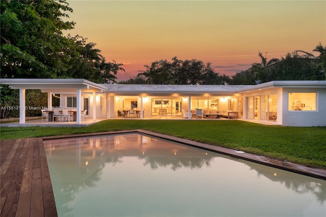 back house at dusk featuring a patio area and outdoor lounge area