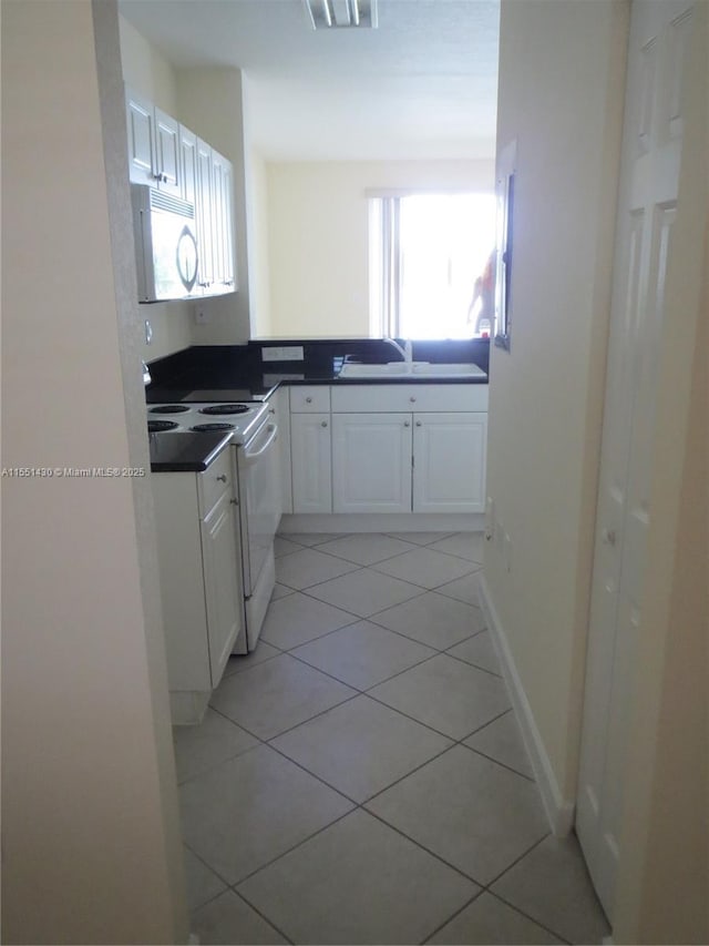 kitchen featuring white cabinetry, white appliances, a wealth of natural light, and light tile patterned floors