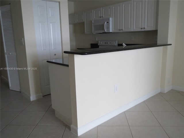 kitchen with kitchen peninsula, stove, and light tile patterned flooring