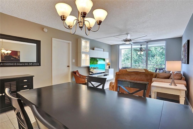 tiled dining space featuring a textured ceiling and ceiling fan with notable chandelier