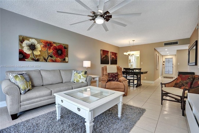 living area featuring baseboards, light tile patterned floors, a textured ceiling, visible vents, and ceiling fan with notable chandelier