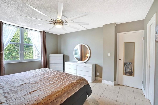 bedroom with a textured ceiling, light tile patterned floors, ceiling fan, and baseboards