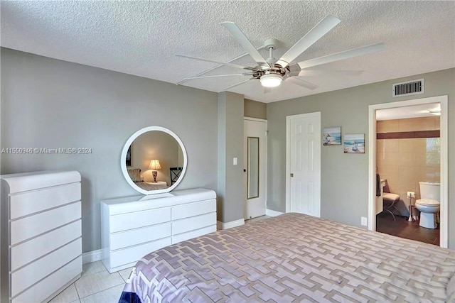 tiled bedroom with a textured ceiling, ceiling fan, and ensuite bathroom