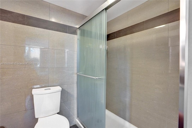 full bath with toilet, an enclosed shower, and tile walls