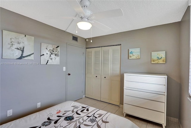 bedroom with light tile patterned floors, ceiling fan, a textured ceiling, a closet, and visible vents