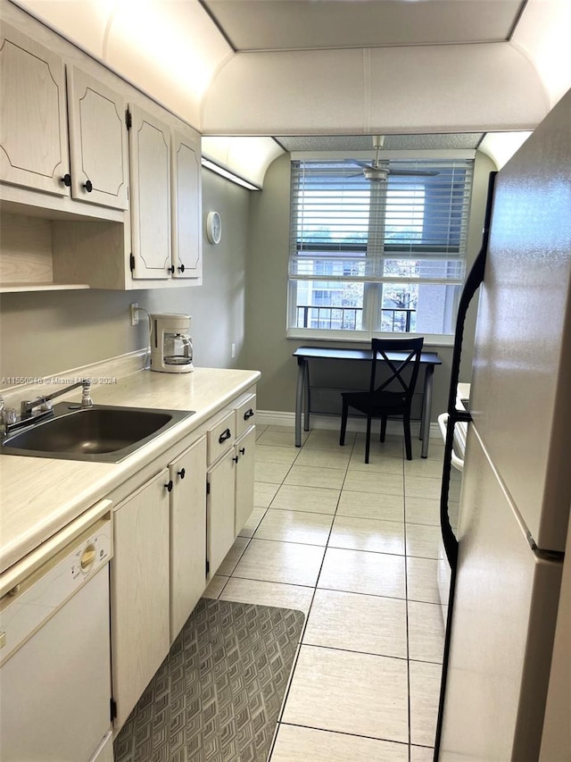 kitchen with light countertops, white dishwasher, a sink, and freestanding refrigerator
