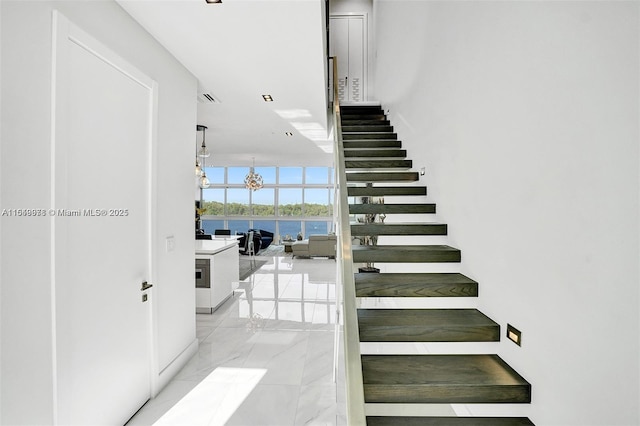 staircase featuring floor to ceiling windows and an inviting chandelier