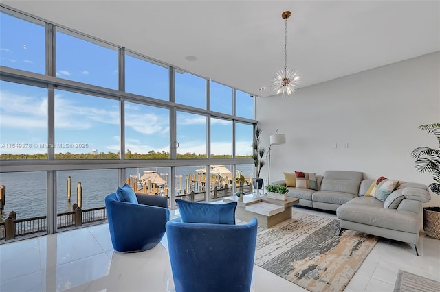 tiled living room featuring a towering ceiling, floor to ceiling windows, a chandelier, and a water view