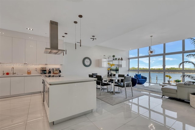 kitchen featuring pendant lighting, white cabinetry, a water view, and island exhaust hood