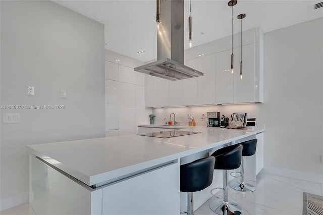 kitchen with island range hood, decorative light fixtures, white cabinetry, a kitchen bar, and black electric cooktop