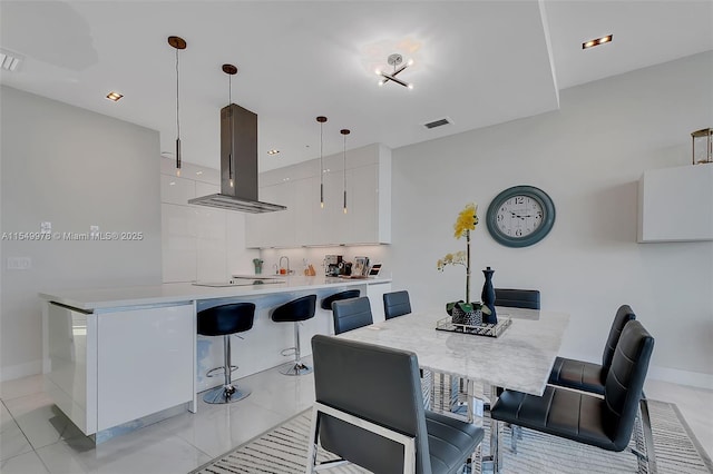 kitchen featuring white cabinetry, hanging light fixtures, a kitchen breakfast bar, island exhaust hood, and kitchen peninsula