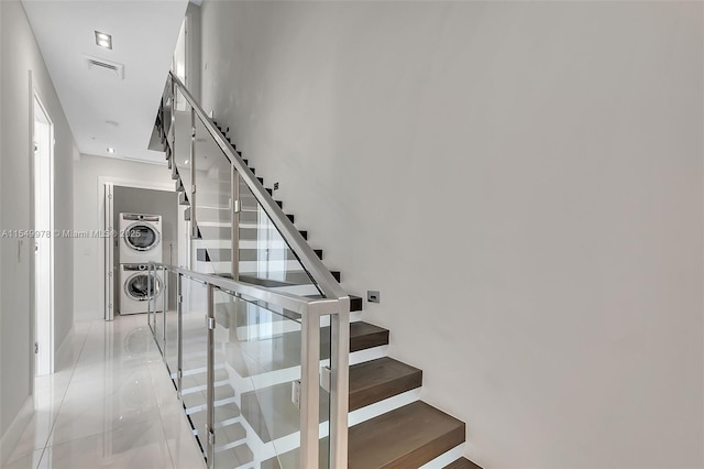 stairway with tile patterned flooring and stacked washing maching and dryer