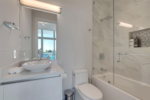 full bathroom featuring vanity, combined bath / shower with glass door, and toilet