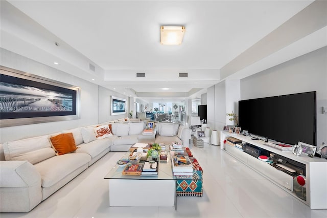 living room with light tile flooring and a raised ceiling