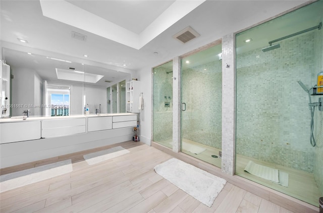 bathroom featuring a tray ceiling, tile flooring, dual bowl vanity, and a shower with shower door