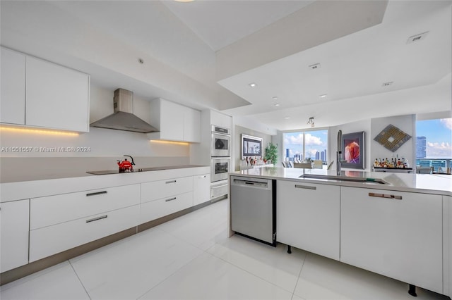 kitchen featuring white cabinets, appliances with stainless steel finishes, and wall chimney exhaust hood