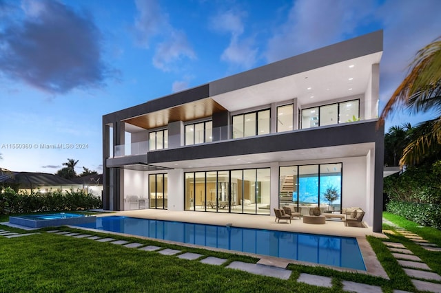 rear view of property with a lawn, outdoor lounge area, a swimming pool with hot tub, and a patio