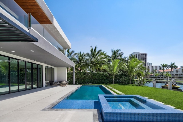 view of swimming pool featuring an in ground hot tub, a water view, a patio area, and a lawn