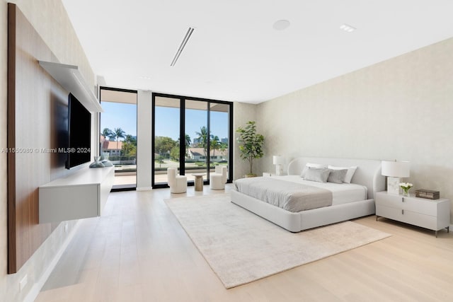 bedroom featuring access to exterior, light hardwood / wood-style flooring, and expansive windows