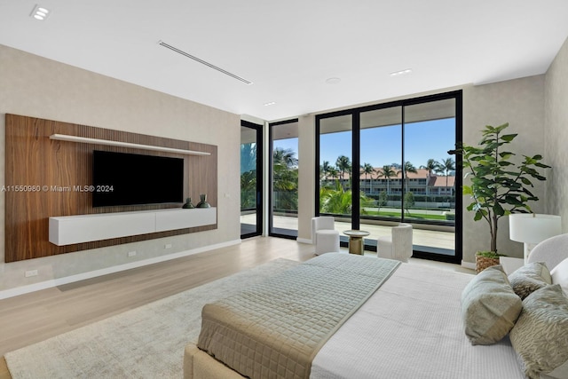 bedroom featuring access to exterior, light hardwood / wood-style floors, and a wall of windows