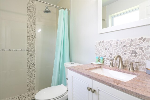 bathroom with curtained shower, large vanity, and toilet