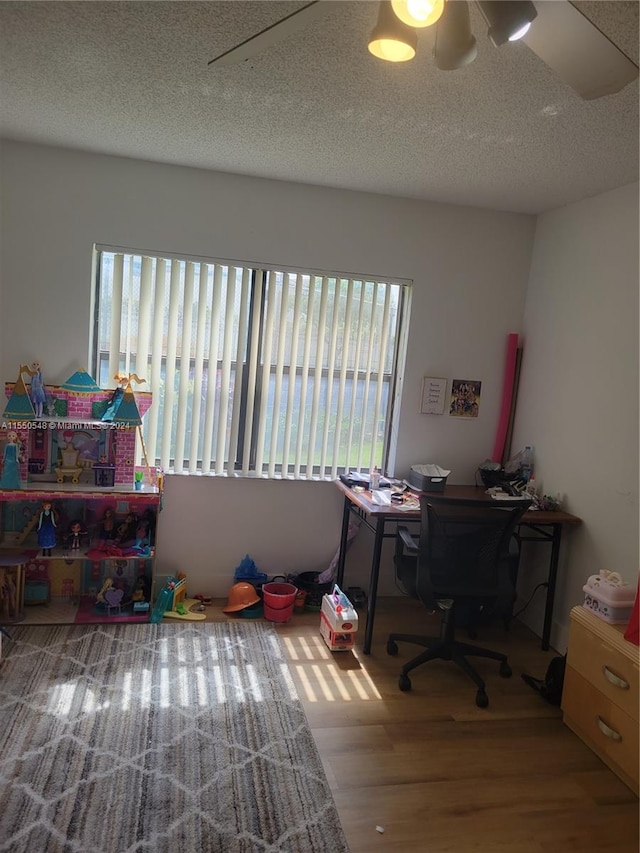 office area with a textured ceiling, wood-type flooring, and a healthy amount of sunlight