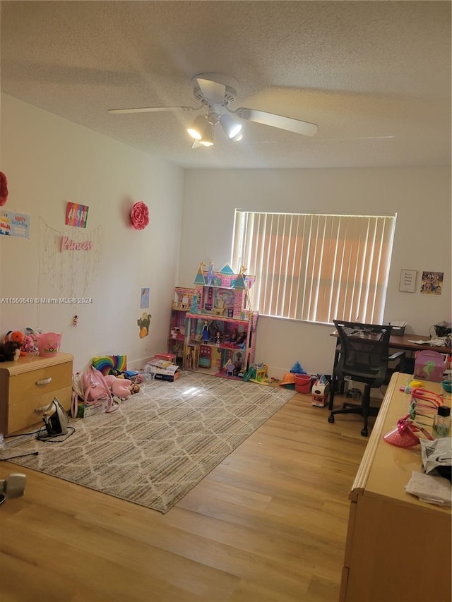 playroom featuring hardwood / wood-style floors, a textured ceiling, and ceiling fan