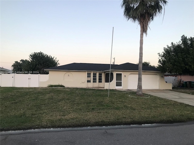 single story home with a garage and a lawn