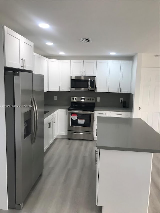 kitchen featuring a center island, hardwood / wood-style floors, white cabinetry, and appliances with stainless steel finishes