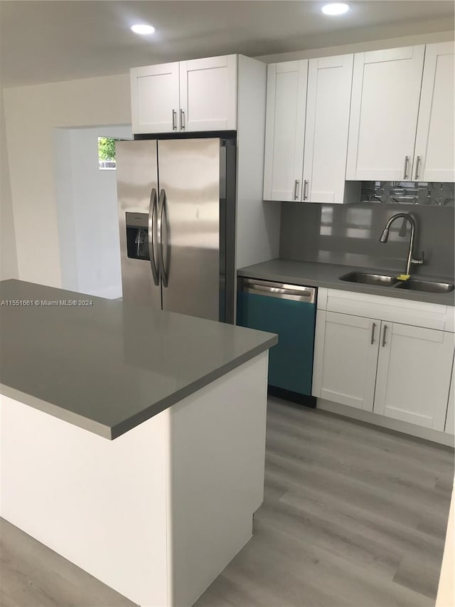 kitchen featuring hardwood / wood-style floors, stainless steel appliances, backsplash, sink, and white cabinetry