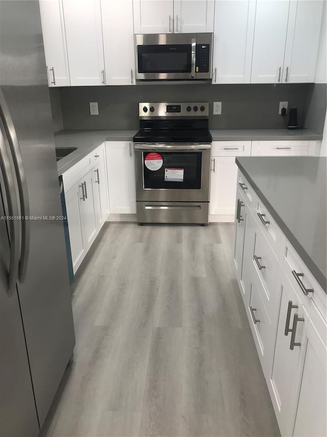 kitchen featuring appliances with stainless steel finishes, white cabinets, and light hardwood / wood-style flooring