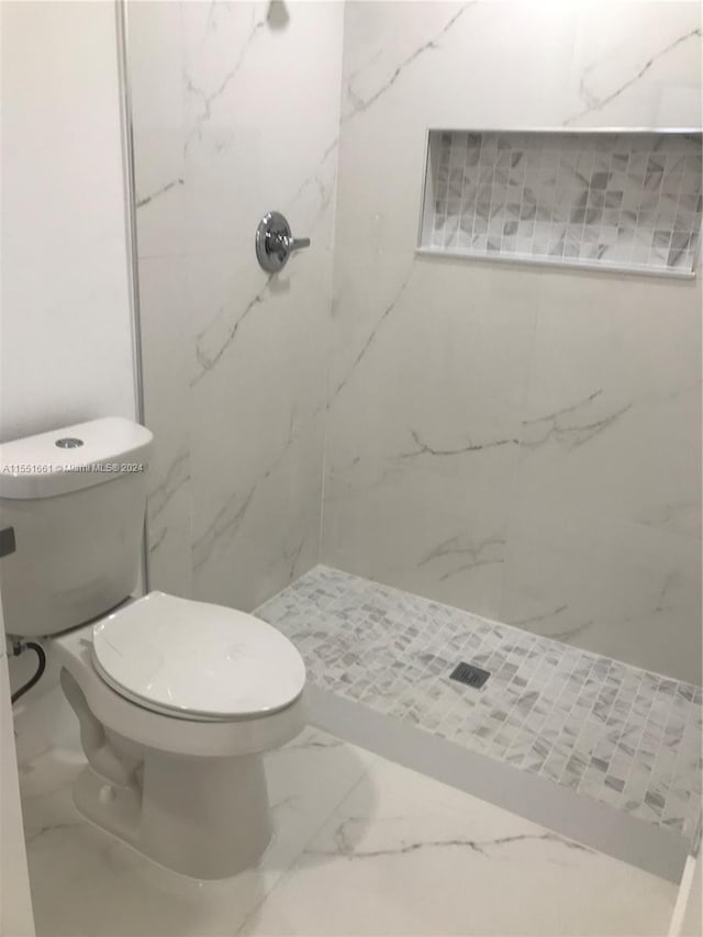 bathroom with a tile shower, tile flooring, and toilet