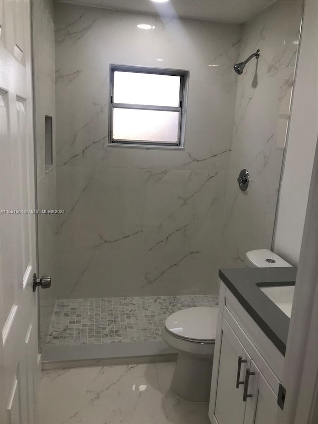 bathroom with a tile shower, tile flooring, toilet, and vanity