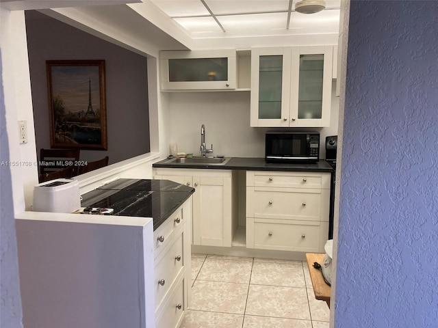 kitchen with white cabinetry, light tile flooring, and sink