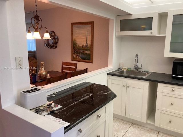 kitchen featuring pendant lighting, light tile floors, sink, white cabinets, and an inviting chandelier