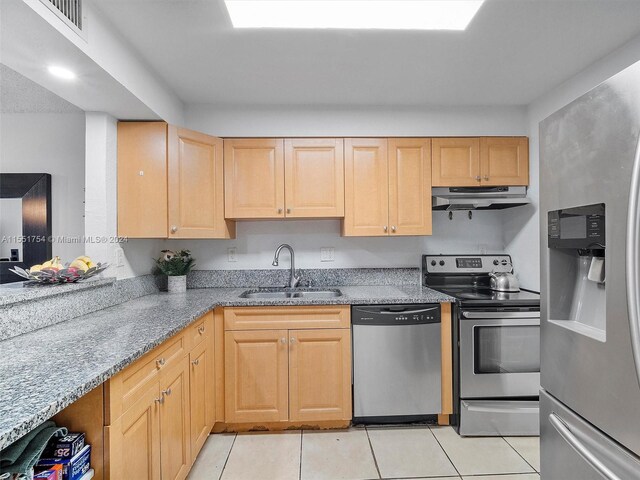 kitchen featuring sink, appliances with stainless steel finishes, light stone counters, light brown cabinets, and light tile patterned floors