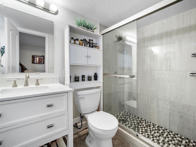 bathroom with a stall shower, a textured ceiling, toilet, and vanity