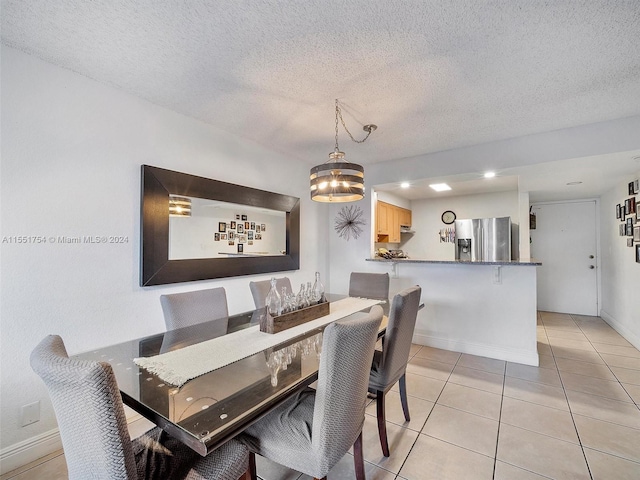 dining area featuring light tile patterned floors, baseboards, and a textured ceiling