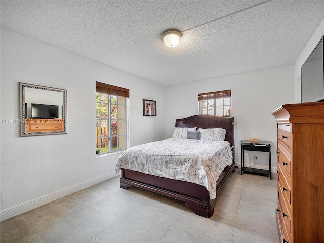 bedroom with a textured ceiling, multiple windows, and baseboards