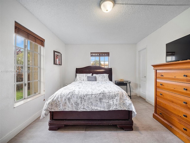 bedroom with a textured ceiling and baseboards