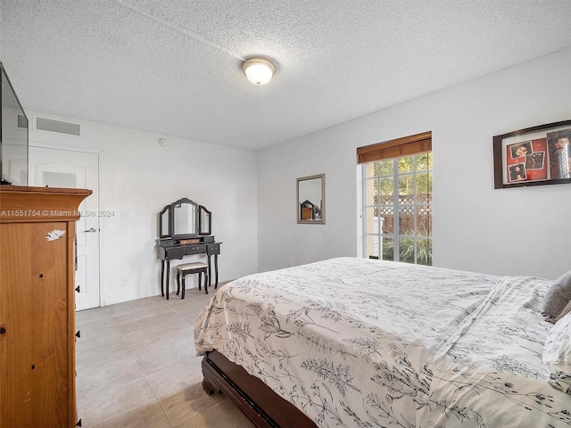 bedroom featuring a textured ceiling, light tile patterned floors, and access to exterior