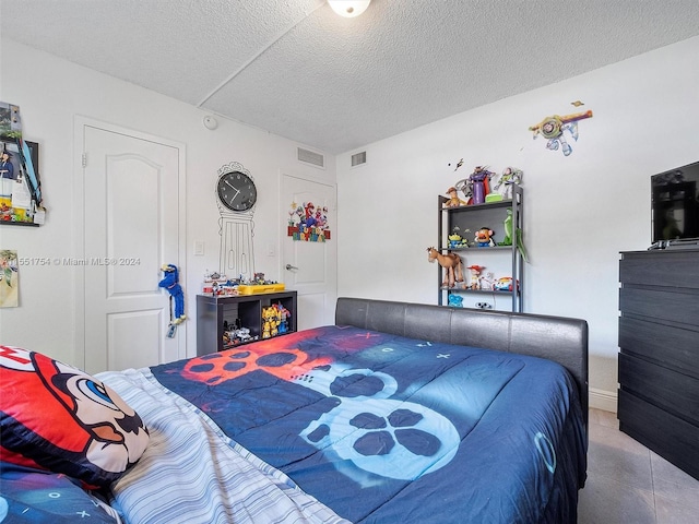 bedroom with visible vents, a textured ceiling, and tile patterned floors