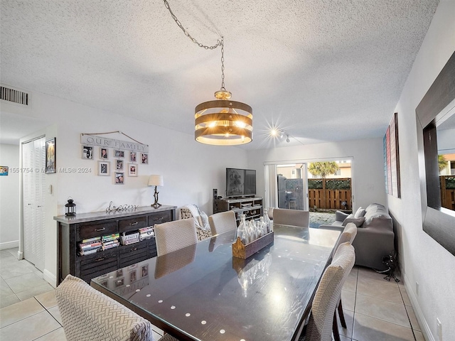 dining room with a textured ceiling, light tile patterned flooring, visible vents, and baseboards