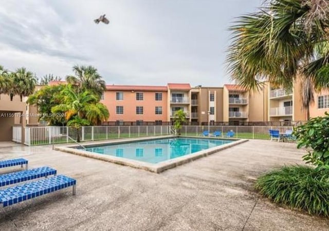 pool with a patio and fence