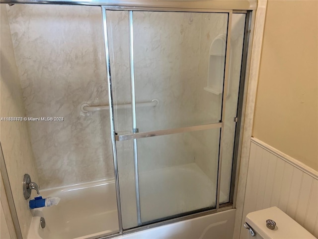 bathroom featuring enclosed tub / shower combo and toilet