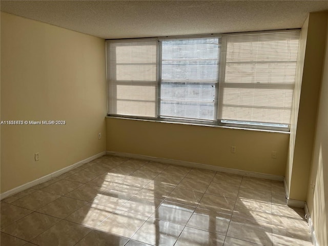 tiled spare room with a textured ceiling and a healthy amount of sunlight