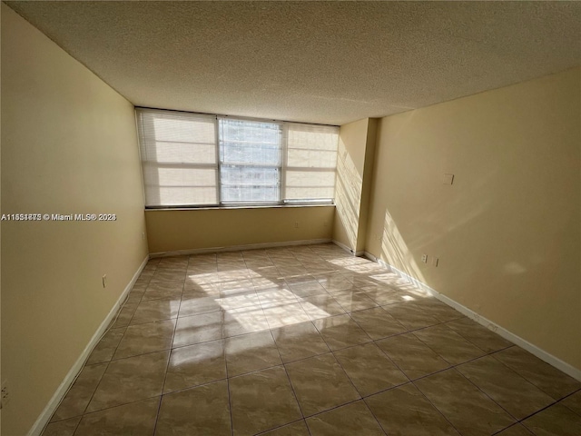 spare room with a textured ceiling and light tile flooring